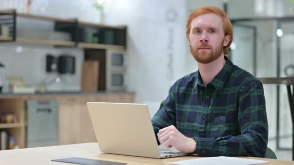 Beard Redhead Man with Laptop Looking at the Camera 