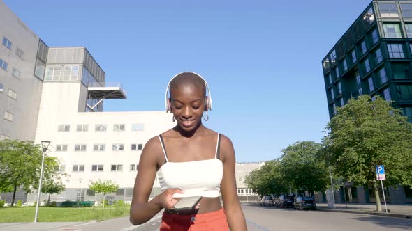 Slow motion shot of young woman using smartphone and walking in city