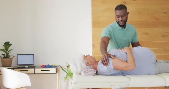 Video of african american male physiotherapist exercising with caucasian senior woman