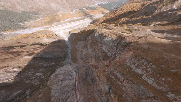 Speed Flight Dive Close Past Mountain Rocky Slopes To Deep Canyon with Dried Stream in Azau Glade