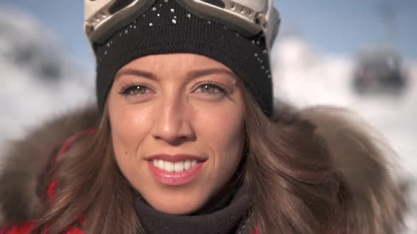 Portrait of a woman smiling lifestyle in the snow at a ski resort with goggles and beanie hat