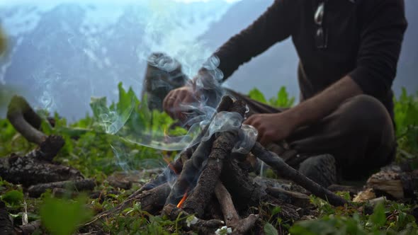A Person Putting Some Tree Branches On A Campfire During Cold Morning - Close Up