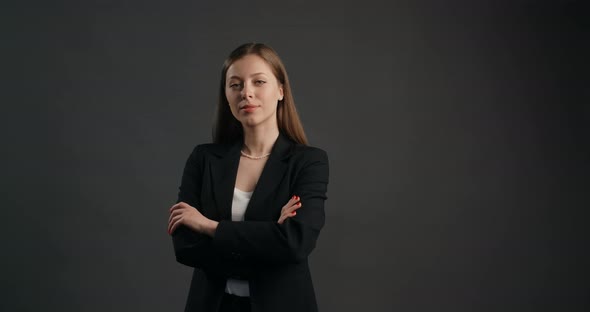 Confident Ambitious Business Woman in Black Suit Watches to the Camera Folded Hands Closed Pose