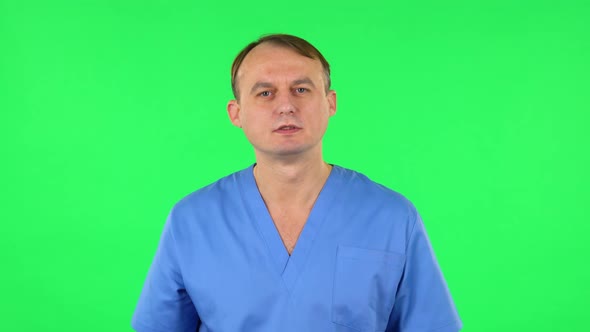 Medical Man Listens Attentively, Nods His Head Pointing Finger at Viewer and Laughs. Green Screen