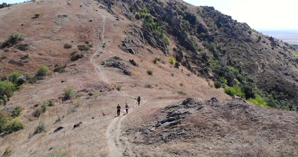 Hikers Walking In The Trail At Macin Mountain Range On A Sunny Summer Day