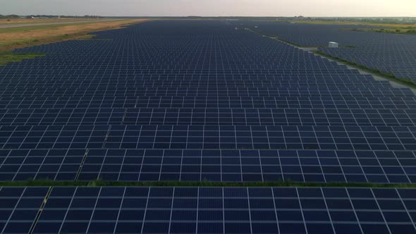 Drone Close Up Flies Over Large Solar Panels at a Solar Farm at Sunny Summer Evening
