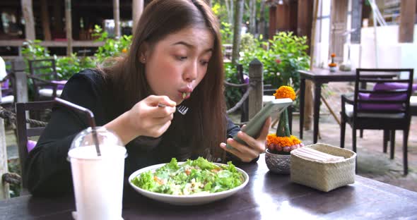 Girl Eating Salad And Using Smart Phone