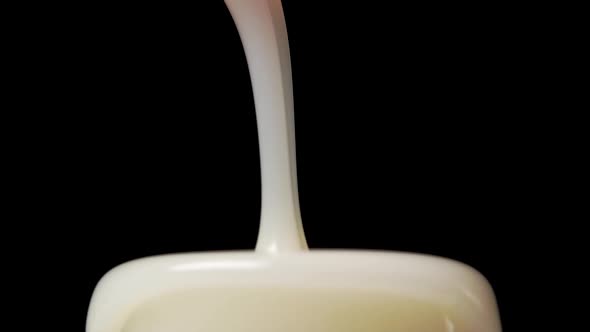 Liquid laundry detergent pours in slow motion and overflows a measuring cup