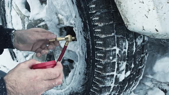 A Man Checks the Car's Tire Pressure