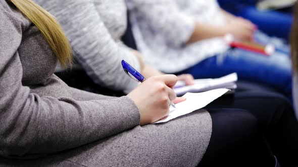 Close-up of female's hands holding pens and making notes at the conference.