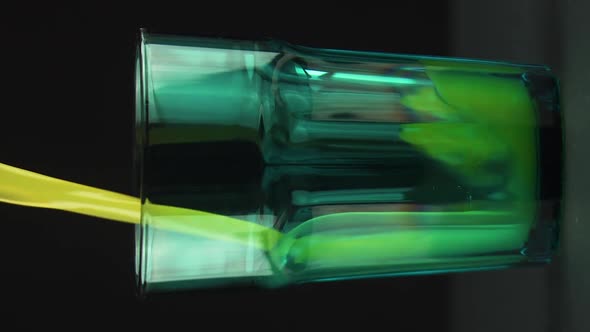 Vertical Video Juice Pouring Into Green Faceted Glass Isolated on Black Background