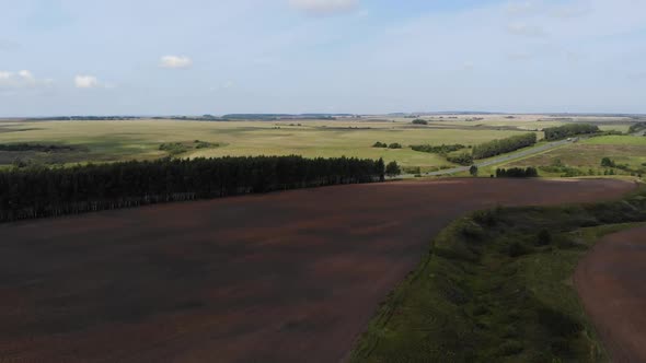 Orange Tractor Plows the Field. Aerial View. 