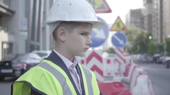 Cute Little Successful Boy Wearing Business Suit and Safety Equipment and Constructor Helmet