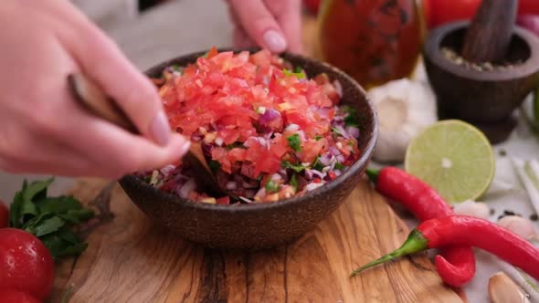 Slow Motion Shot of Woman Mixing Salsa Dip Sauce Ingredients in Wooden Bowl