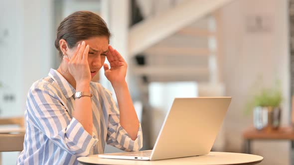 Stressed Young Indian Woman with Laptop Having Headache in Cafe 