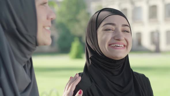 Close-up of Laughing Muslim Woman in Black Traditional Hijab Enjoying Sunny Day Outdoors. Portrait