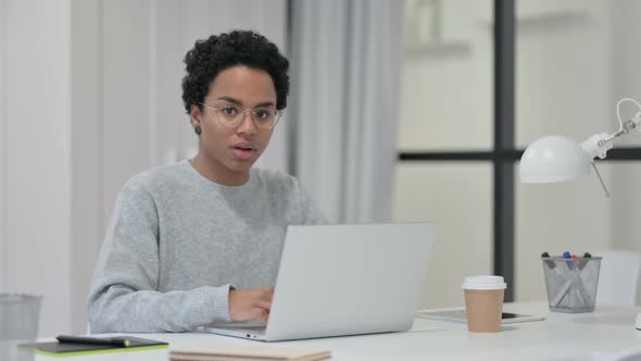 African Woman with Laptop Pointing at Camera