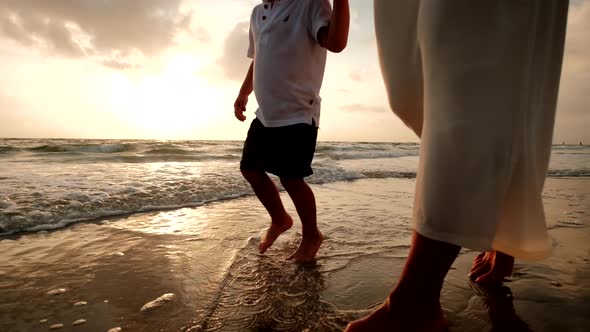 Mother and Son Walk Together on the Beach at Sunset Close Up