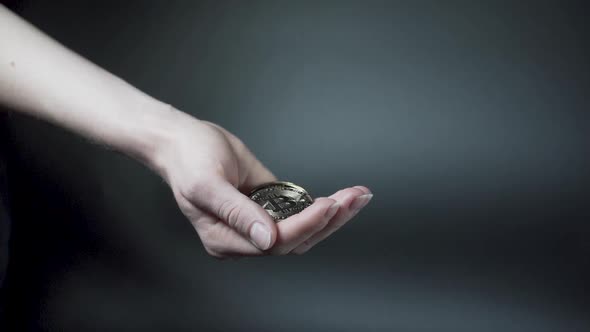 Hand catching falling golden cryptocurrency coins, black background.