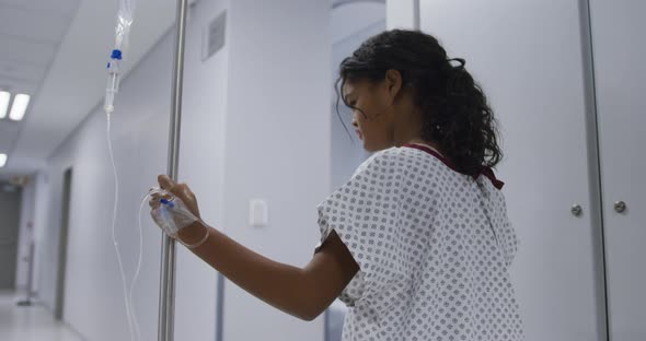 Mixed race girl walking with drip bag in hospital room