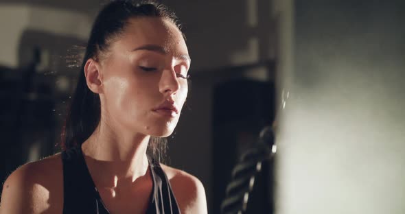 View of Concentrated Female Athlete Pulls Bar with Rope on Simulator in Gym