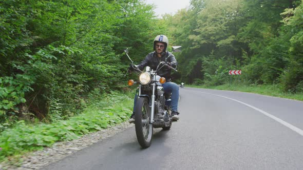 Young man riding a motorcycle on a forest road