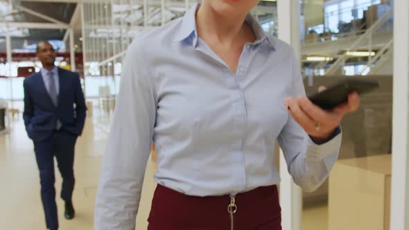 Businesswoman using a smartphone walking in a conference foyer