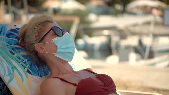 Woman Sunbed In Face Mask On Quarantine Lockdown Coronavirus.New Normal. Vacation Pandemic.