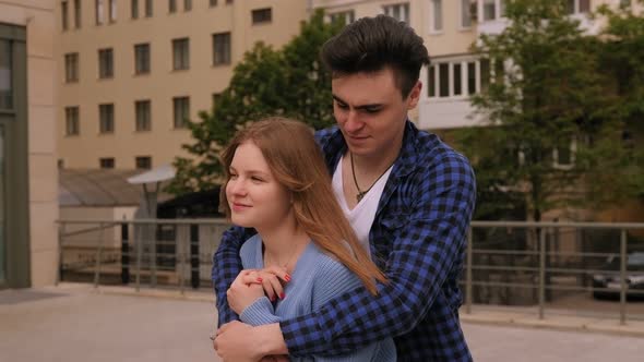 Closeup of a Couple Walking in the City the Guy Hugs the Girl From Behind