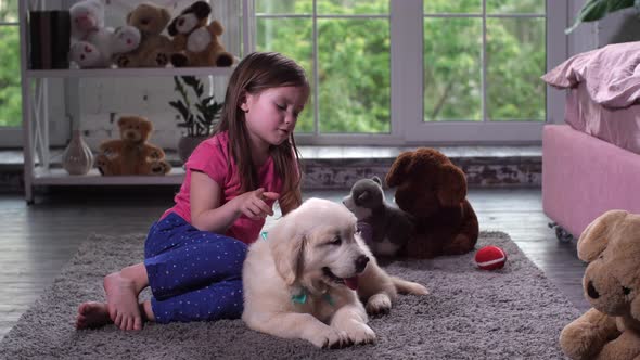 Cute Girl Playing with Puppy Sitting on Floor