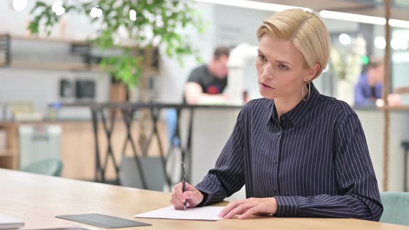 Upset Businesswoman Trying To Write at Work