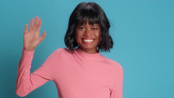 Happy Woman Notices Someone Waves and Greets with Hand