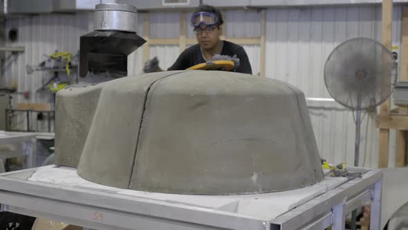 Worker applying mortar on pizza oven in workshop