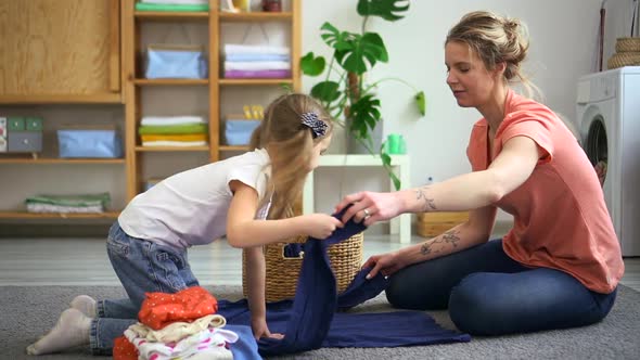 Mother and Daughter Fold Shirt Clothes Together in Laundry Room Spbd