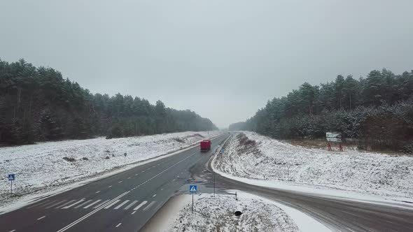 Winter highway, car and truck traffic. On the sides of the forest.