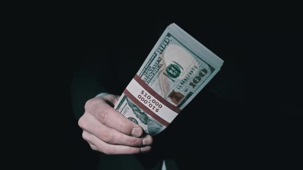Stack of 10000 American Dollars in Bundle in Male Hands on Black Background