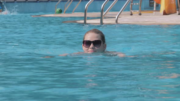 Portrait of Woman Swimming in Pool in Sunglasses During Summer Vacation
