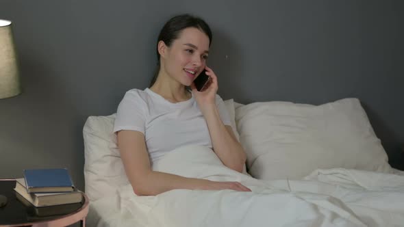 Young Woman Talking on Smartphone in Bed