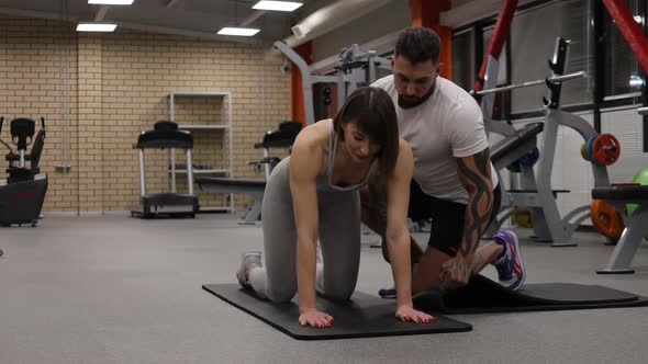 Sportswoman Training with Personal Instructor in Gym