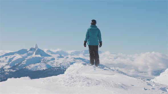 Adventurous Girl on Top of a Beautiful Snowy Mountain During a Vibrant and Sunny Winter Day