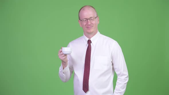 Mature Bald Businessman Turning Coffee Cup Upside Down