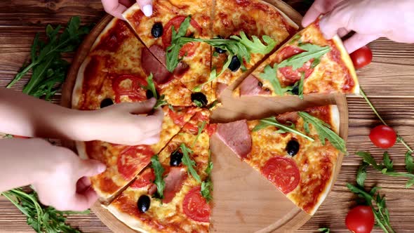 People Hands Taking the Slices Of Pizza. Pizza and Hands close up over wooden background.