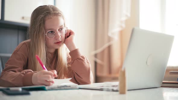 Beautiful 10 Years Old Girl Doing Her Homework Using a Laptop