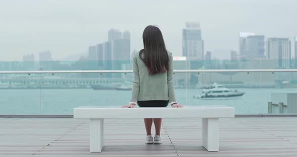 Woman sitting on bench and looking at the sea in Hong Kong