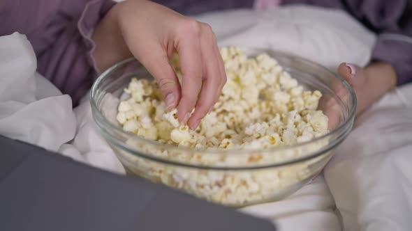 Closeup Bowl with Popcorn and Slim Female Caucasian Hands Taking Snack Watching Movie Online on