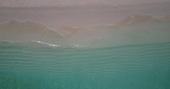 Daytime above tourism shot of a sandy white paradise beach and blue sea background in vibrant 4K