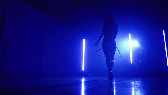 Young Woman in Sexy Outfit Moves Plasticly to Music in Blue Studio with Long Lamps