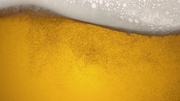Close-up of the contents of a glass of beer. Beer slowly sways in a glass, waves, bubbles and foam.