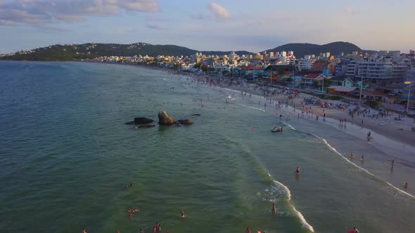 Aerial view of tourists bathing and swimming on the sea in Bombas Beach at golden hour