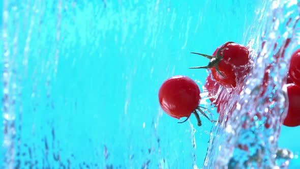 Fresh Cherry Tomatoes Flying Into Water Cascade In Slow Motion 